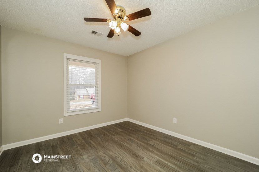 the spacious living room with a ceiling fan and a window