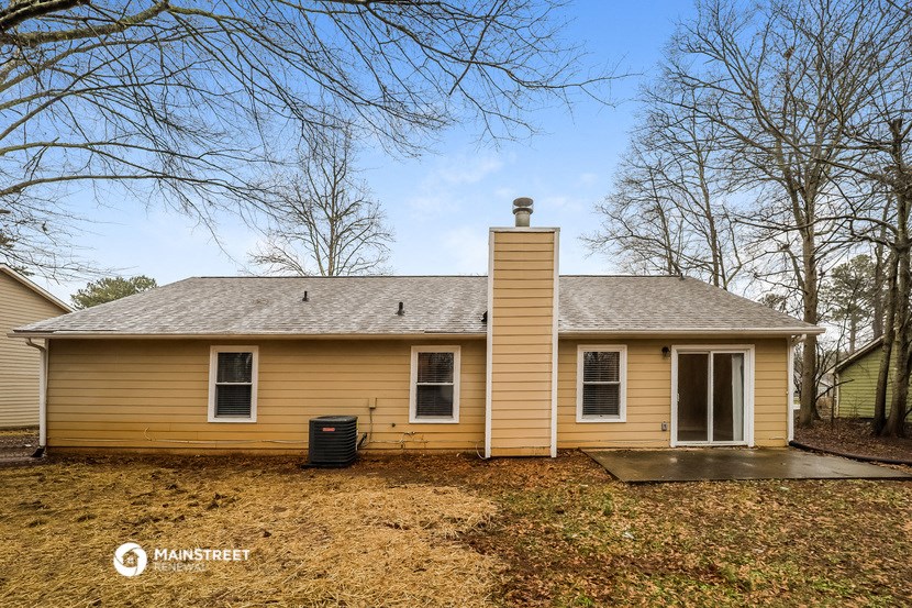 the front of a yellow house with a yard and trees