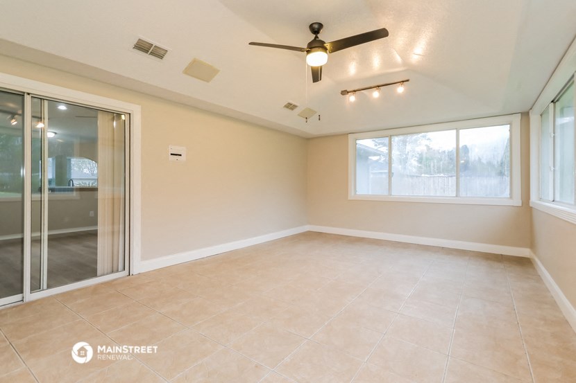 an empty living room with a ceiling fan and a window