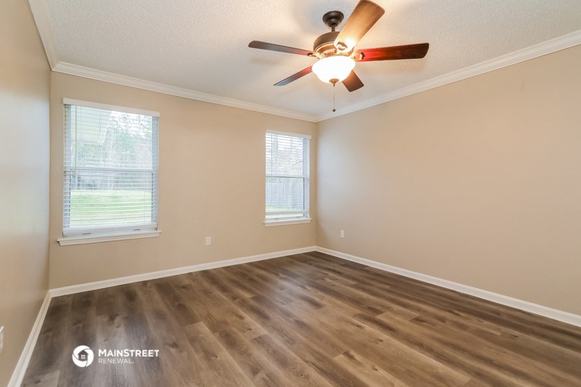 the spacious living room with hardwood floors and a ceiling fan