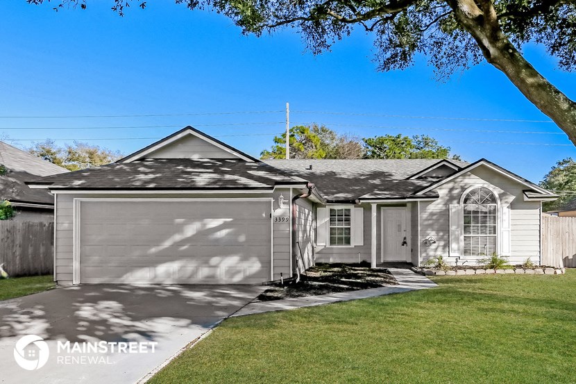 a gray house with a lawn and a tree