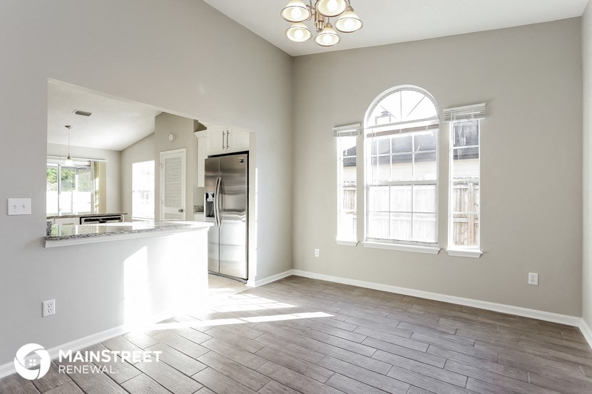 an empty living room with a kitchen and a large window