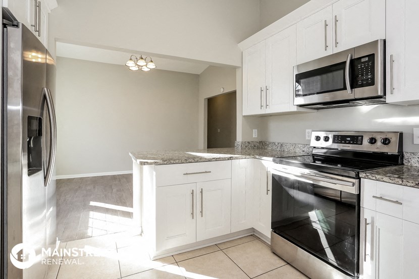 a kitchen with white cabinets and stainless steel appliances