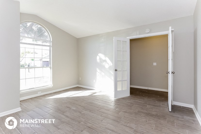 an empty living room with a white door and a window