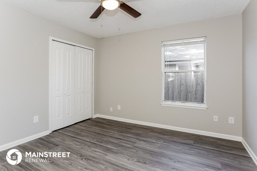 the living room of an apartment with wood flooring and a ceiling fan