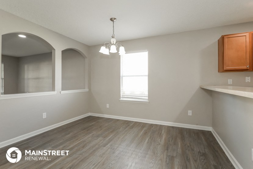 an empty living room with wood flooring and a window