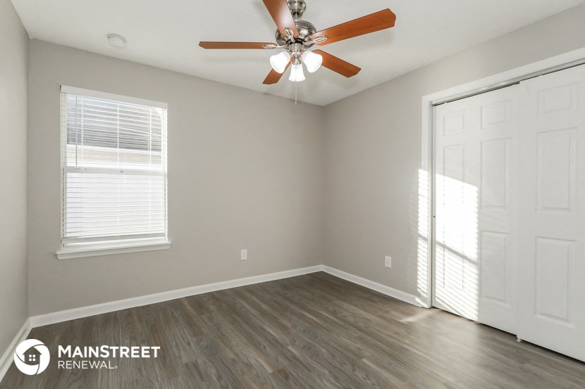 the spacious living room with ceiling fan and window
