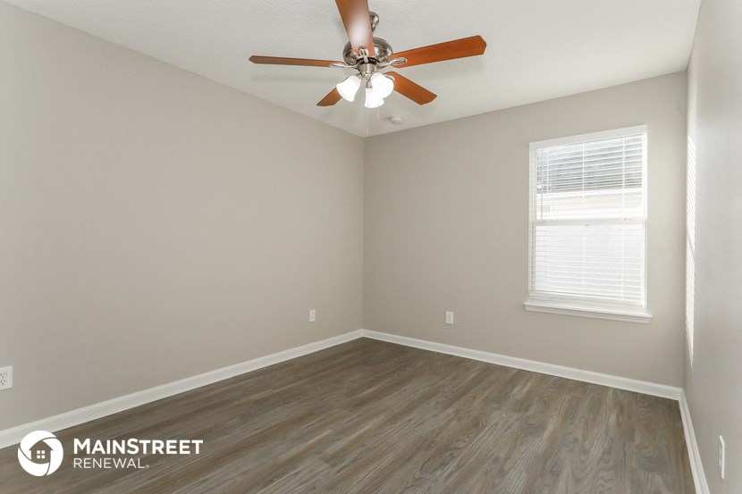the interior of a room with wooden floors and a ceiling fan