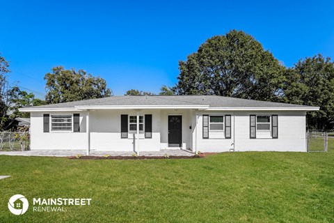 a small white house with a lawn and a fence