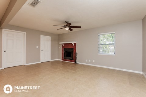 the living room with fireplace and tile flooring and ceiling fan
