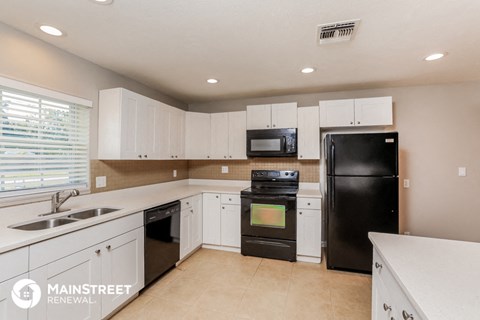 a large kitchen with white cabinets and black appliances