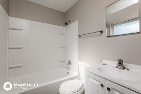 a white bathroom with a white toilet and a sink and a tub