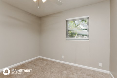 the upstairs bedroom has a window and beige carpet