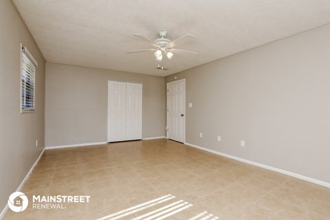 the spacious living room with ceiling fan and tile flooring