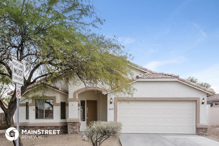 a house with a garage door and a tree in front of it