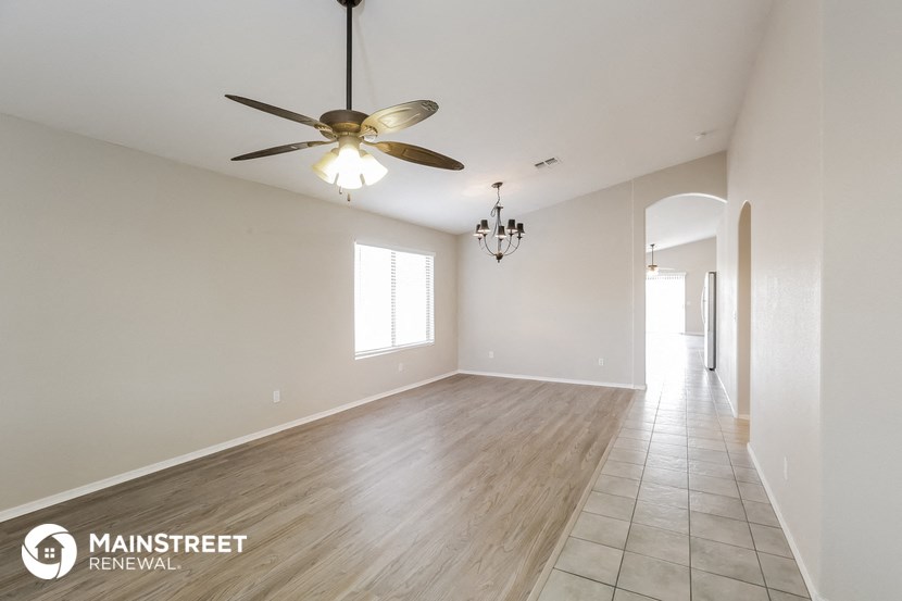 an empty living room with a ceiling fan and a hallway