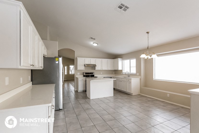 a large kitchen with white cabinets and a large window
