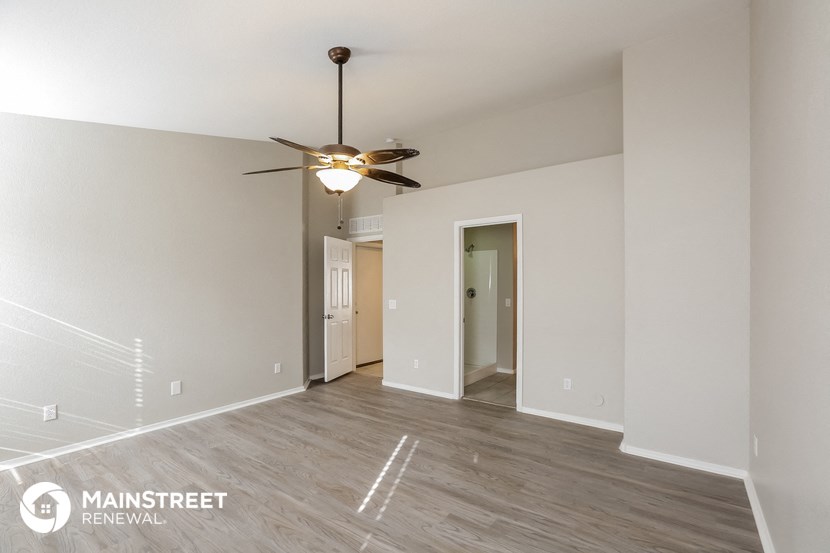 a spacious living room with white walls and a ceiling fan