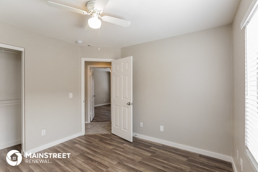 the spacious living room with a ceiling fan and wood flooring