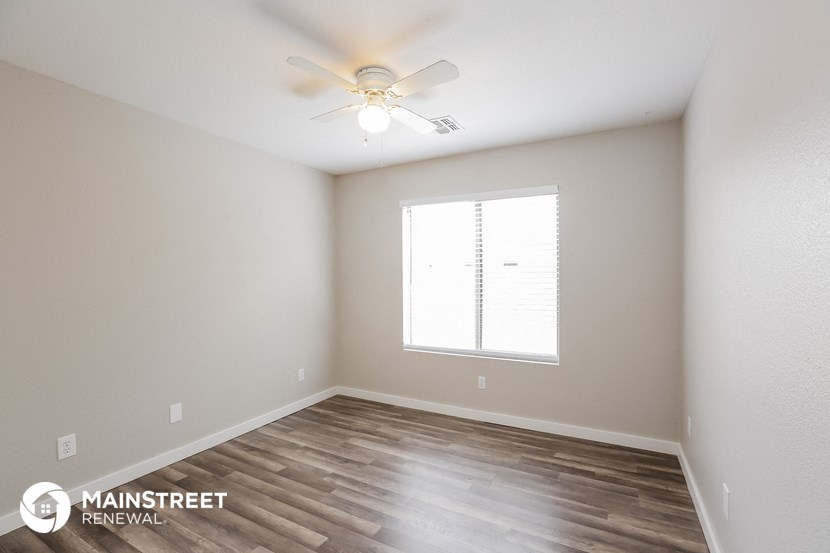the spacious living room with ceiling fan and wood flooring