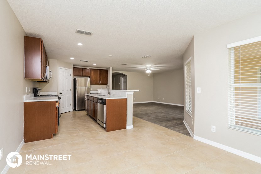 an open kitchen and living room with white appliances and tile flooring