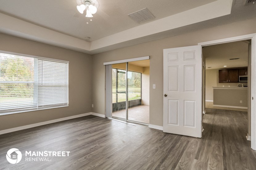 an empty living room with a white door and a window