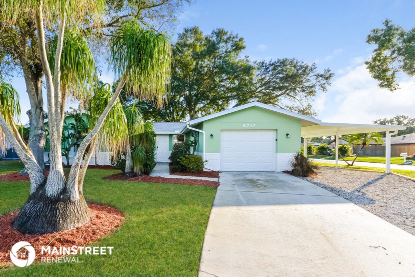 a green house with a white garage door
