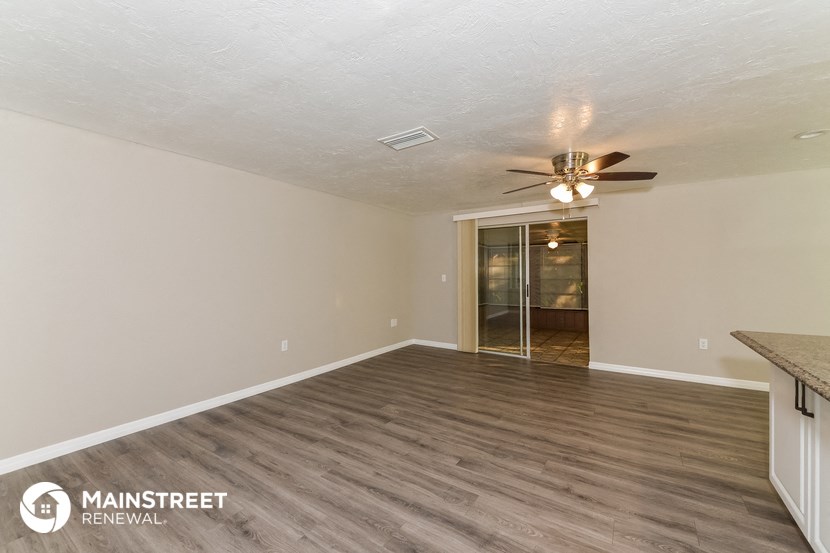 an empty living room with wood flooring and a ceiling fan
