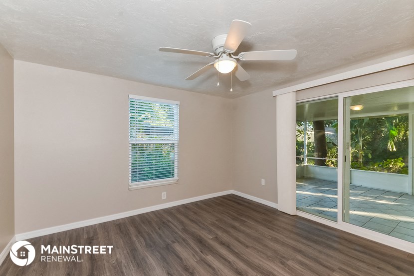 an empty living room with a ceiling fan and a window