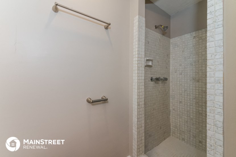 a walk in shower in a bathroom with white tile and a shower curtain