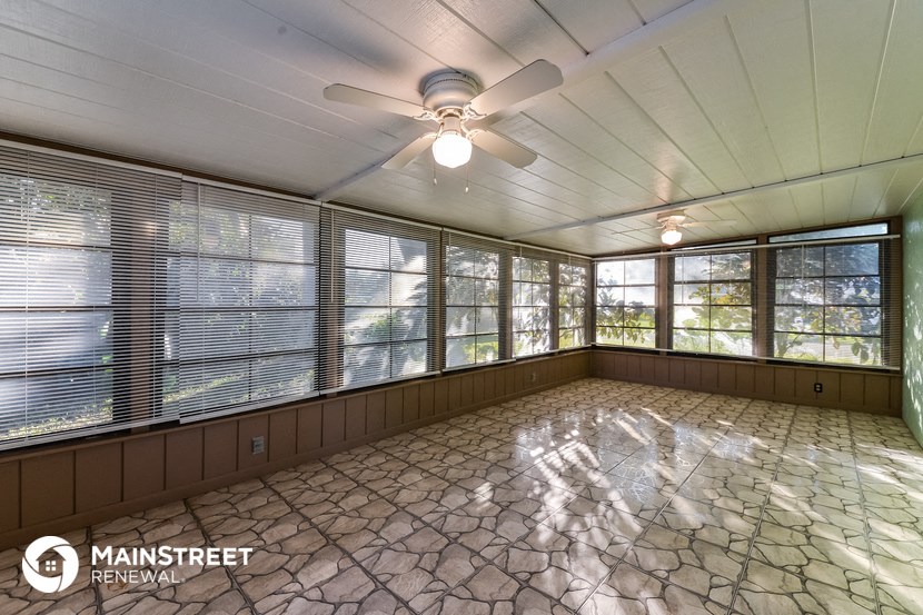 an empty room with large windows and a ceiling fan