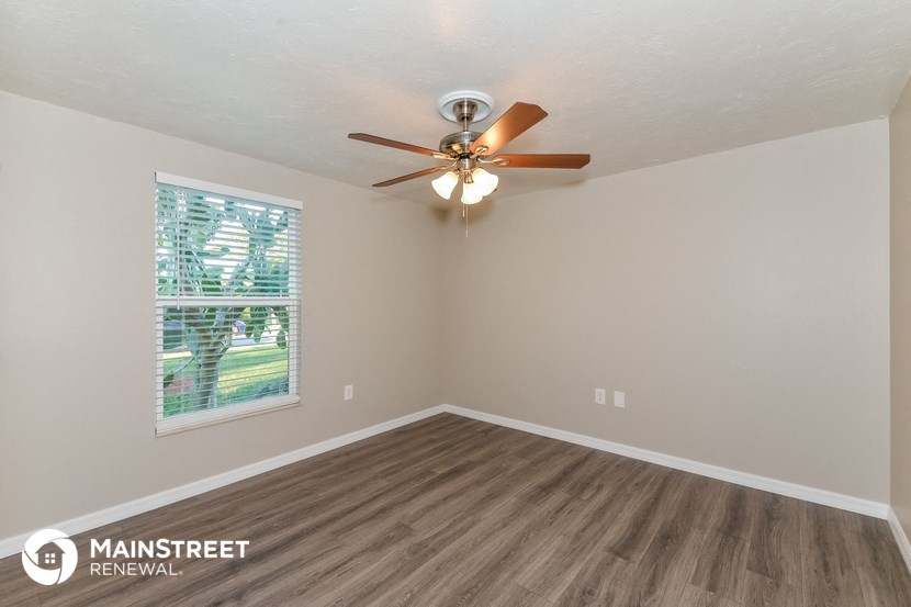 an empty living room with a ceiling fan and a window