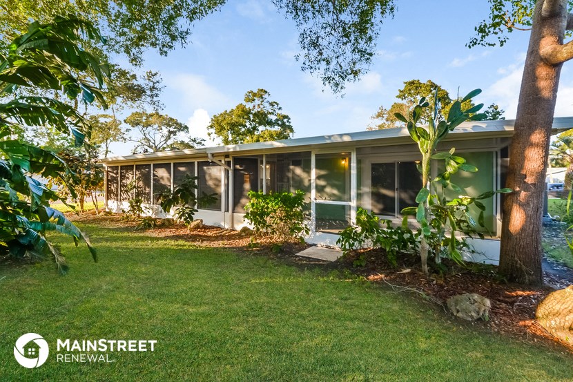 the front of the house with the lawn and trees