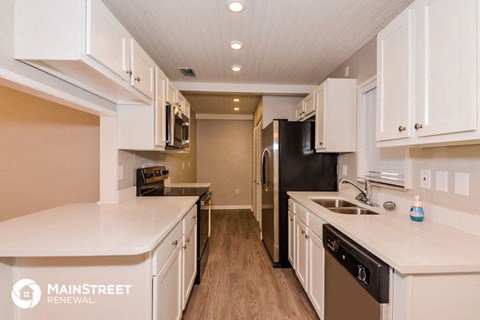 a kitchen with white cabinets and a black refrigerator