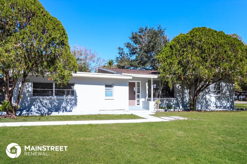 a white house with a lawn and trees
