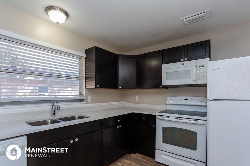 a kitchen with black cabinets and white appliances and a window