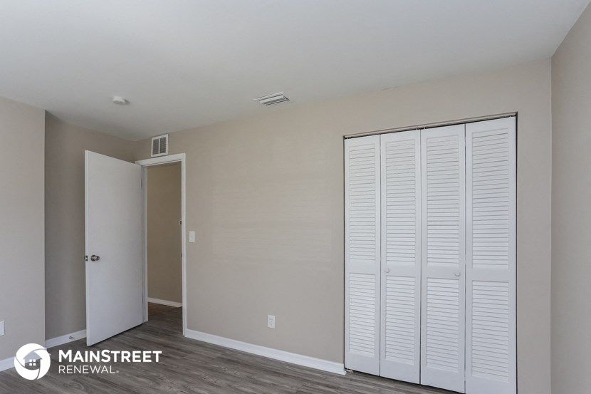 the closet in a master bedroom with white shutters on the closet doors