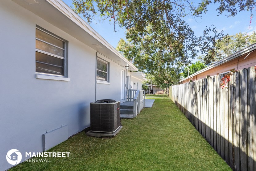 a small yard with a white house and a wooden fence