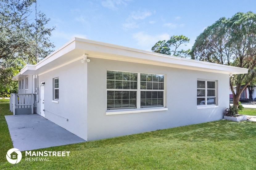 the exterior of a white house with a lawn and trees
