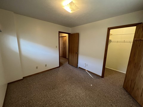A room with a carpeted floor and a doorway leading to another room.