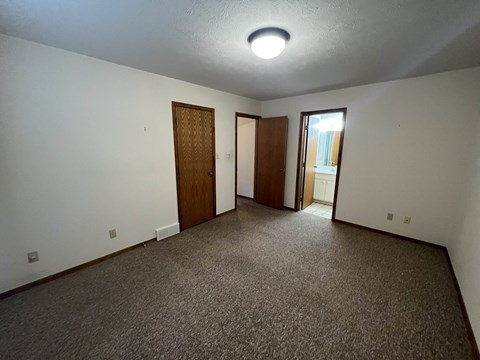 A room with carpeted floor and two doors.