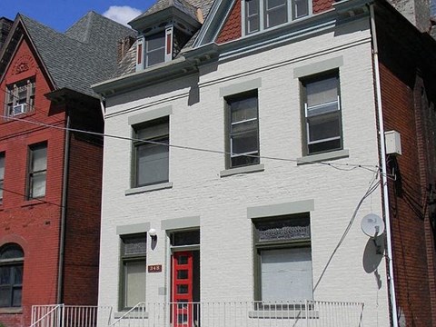 A white building with a red door and windows.
