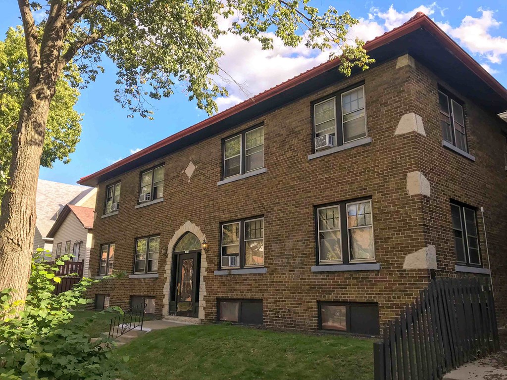 a brick house with a yard and a tree