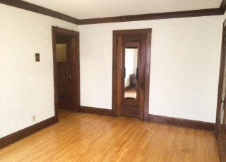 an empty living room with a wooden floor and a door