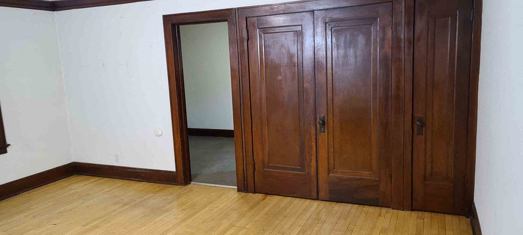 an empty room with wooden floors and a closet