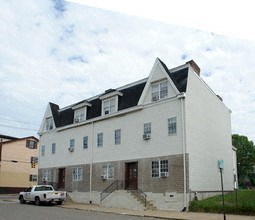 A white building with a black roof and a white car parked in front.
