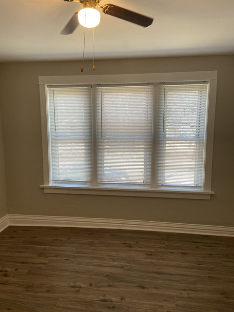 a bedroom with a large window and a ceiling fan