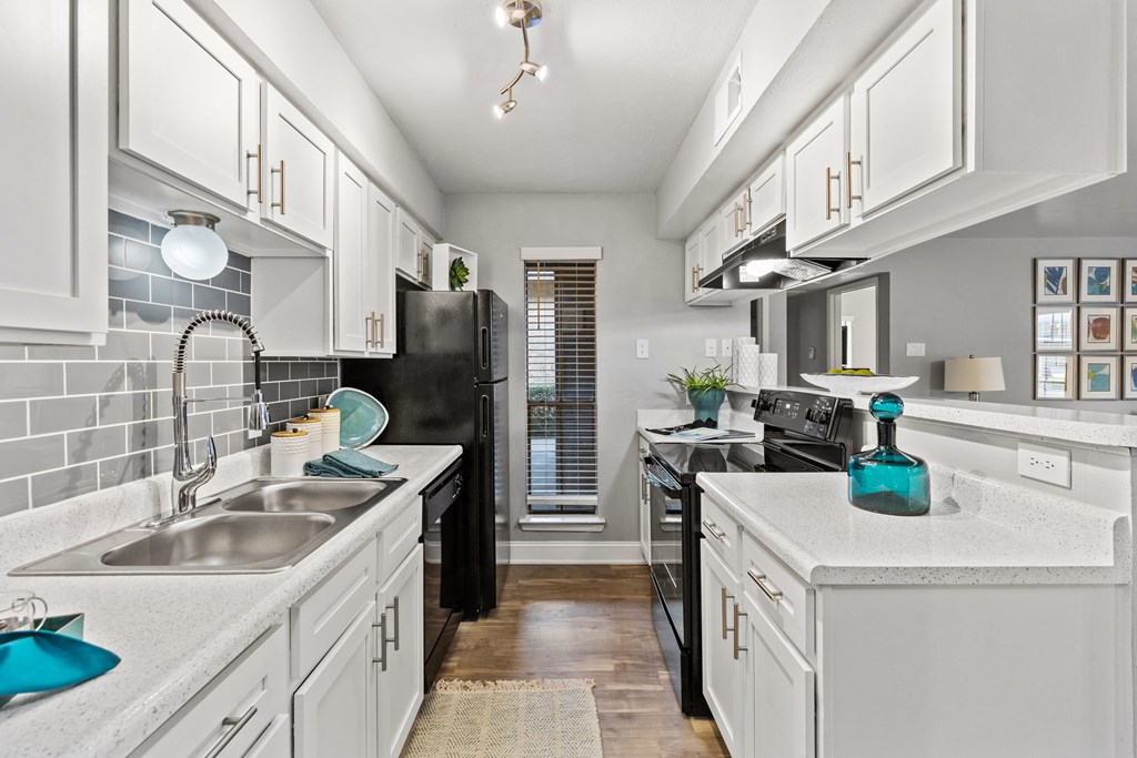 a kitchen with white cabinets and black appliances and a sink