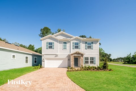a white house with blue shutters and a brick driveway