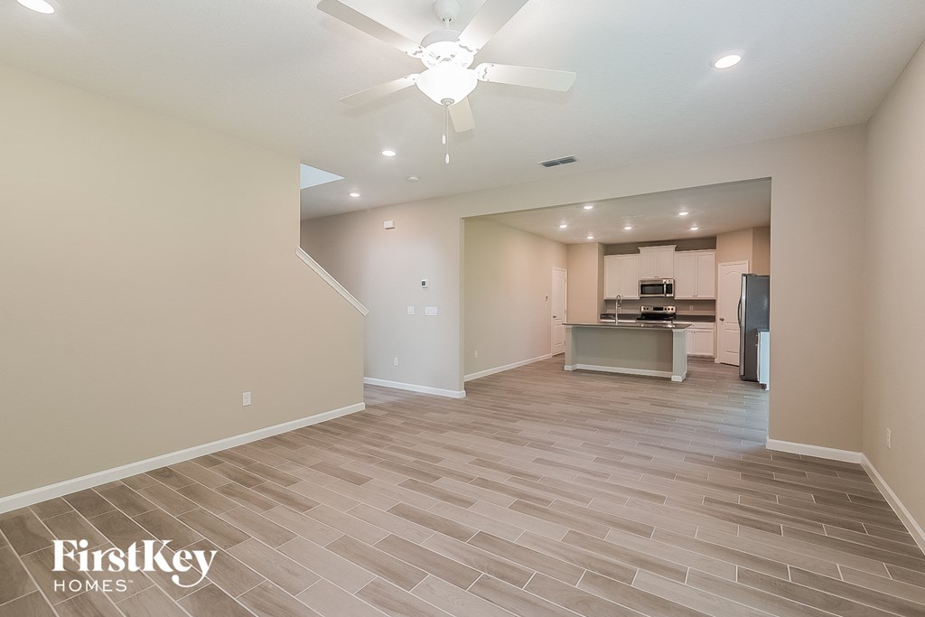 the spacious living room and kitchen with a ceiling fan